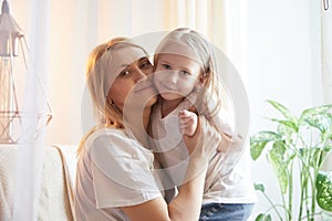 Happy loving family with mother and daughter having hugs in living room. Woman mom and small child girl inside of the