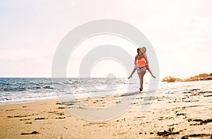 Happy loving family mother and daughter running and having fun on the beach at sunset - Mom piggyback her kid next to ocean