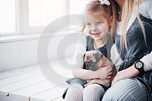 Happy loving family. Mother and her daughter child girl playing and hugging adorable pug