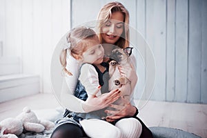 Happy loving family. Mother and her daughter child girl playing and hugging adorable pug