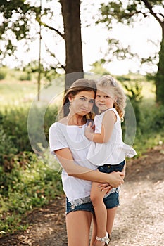 Happy loving family. Mother and her daughter child girl playing and hugging. alley of big trees