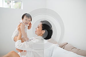 Happy loving family. Mother and her daughter child girl playing and hugging on bed