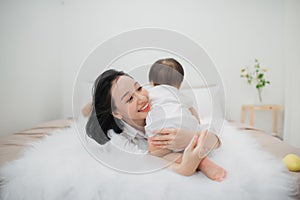 Happy loving family. Mother and her daughter child girl playing and hugging on bed