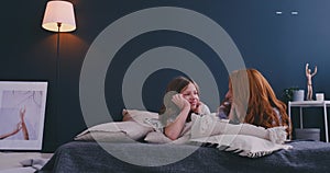 Happy loving family. Mother and her daughter child girl playing and hugging on the bed in bedroom.