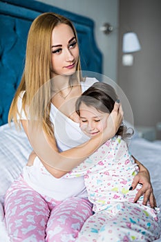 Happy loving family. Mother and her daughter child girl playing and hugging in the bed at home