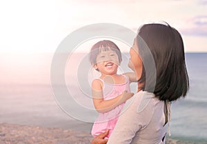 Happy loving family. Mother and her daughter child girl playing and hugging on sea background in the evening