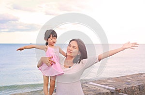 Happy loving family. Mother and her daughter child girl playing and hugging on sea background in the evening