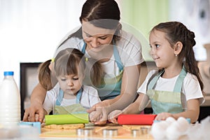 Happy loving family mother and her daughters are preparing bakery together. Mom and kids are cooking cookies and having fun in the