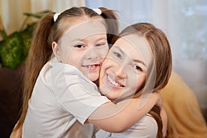 Happy loving family. Mother and her teenager daughter child girl playing and hugging in living room with flowers