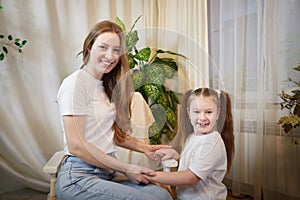 Happy loving family. Mother and her teenager daughter child girl playing and hugging in living room with flowers