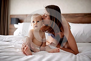 Happy loving family. Mother kissing her child son on the bed