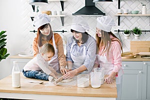 Happy loving family are preparing bakery together. Grandmother, two daughters and child granddaughter girl are baking