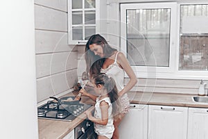 Happy loving family preparing cheesecakes for breakfast together. Beautiful young Mom and her cute child daughter girl cooking and