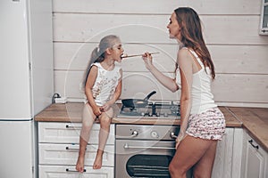 Happy loving family preparing cheesecakes for breakfast together. Beautiful young Mom and her cute child daughter girl cooking and