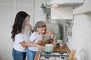 Happy loving family preparing dinner together. Smiling Mom and child daughter girl cooking and having fun in the kitchen