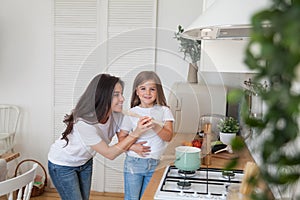 Happy loving family preparing dinner together. Smiling Mom and child daughter girl cooking and having fun in the kitchen. Homemade