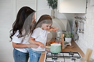 Happy loving family preparing dinner together. Smiling Mom and child daughter girl cooking and having fun in the kitchen. Homemade