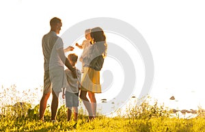 Happy loving family walking outdoor in the light of sunset. Father, mother, son and daughter.