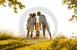 Happy loving family walking outdoor in the light of sunset. Father, mother, son and daughter.