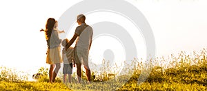 Happy loving family walking outdoor in the light of sunset. Father, mother, son and daughter.