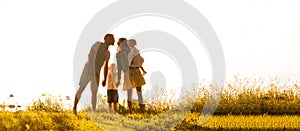 Happy loving family walking outdoor in the light of sunset. Father, mother, son and daughter.