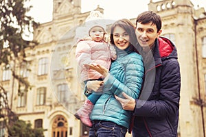 Happy loving family(mother, father and little daughter kid) outdoors walking having fun on a park in autumn season. Fallen yellow