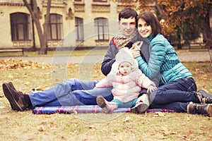 Happy loving family(mother, father and little daughter kid) outdoors walking having fun on a park in autumn season. Fallen yellow