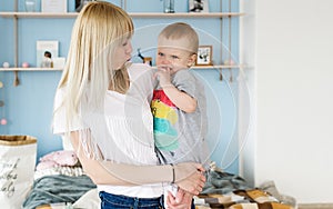 Happy loving family. Young blonde mother playing with her baby in the bedroom.