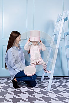 Happy loving family. young Mother in blue and her little daughter in pink clothes playing with pink gift box and blue ladder on