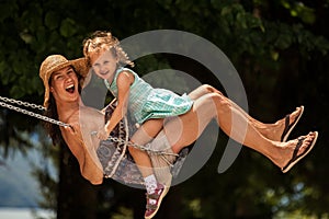 HHappy loving family! Young mother and her child daughter swinging on the swings and laughing a summer evening outdoors, beautiful