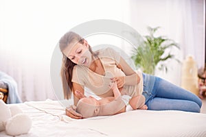 Happy loving family. A young mother plays with her child in the bedroom