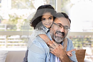 Happy loving Indian grandfather piggybacking sweet beloved preschool granddaughter