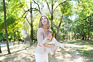 Happy loving mother and her baby having fun outdoors in the park