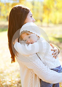 Happy loving mother hugging child in autumn day
