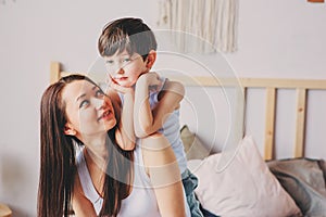 Happy loving mother hugs with child son in the morning in bed