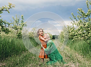 a happy and loving mother hugs her little daughter in an apple orchard