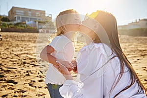 Happy loving mother kissing daughter on the beach