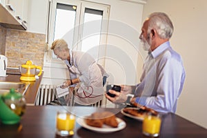 Loving senior couple having fun preparing healthy food on breakfast in the kitchen