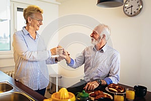 Loving senior couple having fun preparing healthy food on breakfast in the kitchen