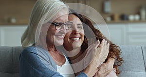 Happy loving senior mom hugging cheerful adult daughter woman