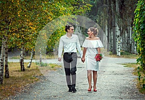 Happy loving wedding couple walking in the autumn park