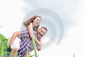 Happy loving young adult couple spending time on the field on sunny day