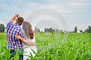 Happy loving young adult couple spending time on the field on sunny day