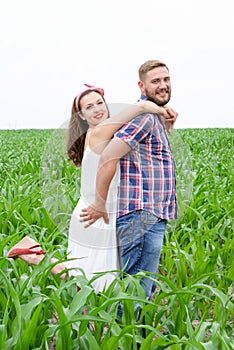 Happy loving young adult couple spending time on the field on sunny day