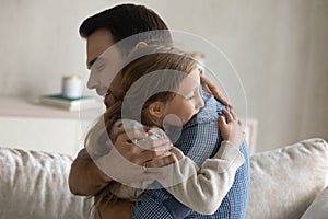 Happy loving young father cuddling small daughter.