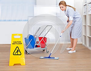 Happy maid cleaning floor with mop