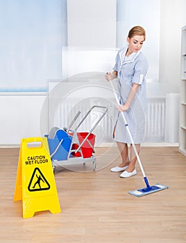 Happy maid cleaning floor with mop