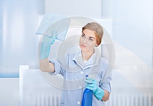 Happy maid cleaning glass