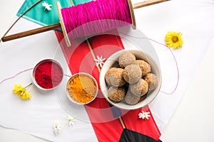 Happy Makar Sankranti Festival - Tilgul or Til ladoo in a bowl or plate with haldi kumkum and flowers with Fikri /Reel/Chakri /Spo