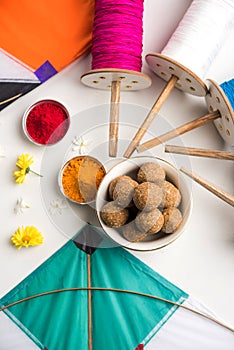 Happy Makar Sankranti Festival - Tilgul or Til ladoo in a bowl or plate with haldi kumkum and flowers with Fikri /Reel/Chakri /Spo